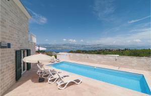 een zwembad met 2 stoelen en een parasol bij Cozy Home In Postira With House Sea View in Postira