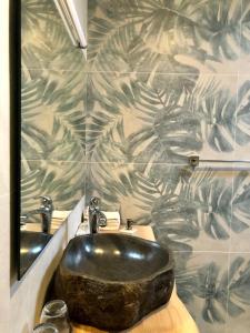 ein Bad mit einem schwarzen Waschbecken und einem Spiegel in der Unterkunft B&B L'Eden in Aigle