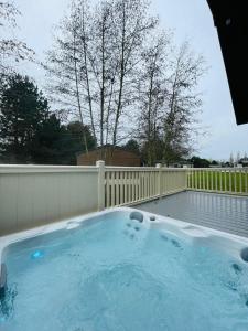 a hot tub in a backyard with a fence at Happy Days Lodge with Hot Tub in York