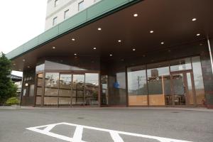 un grand bâtiment en verre avec beaucoup de fenêtres dans l'établissement Ariston Inn Kanda Kitakyusyu Airport, à Kanda