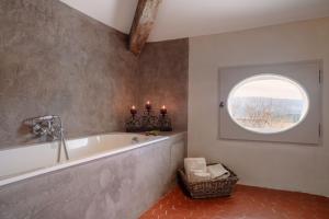 Luxurious Provencal Village House, Walk to Village Pool في روستريل: حمام مع حوض استحمام و نافذة مستديرة