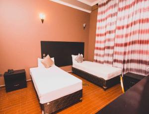 Zimmer mit 2 Betten und einem Vorhang in der Unterkunft Panone Hotels - Sakina in Arusha