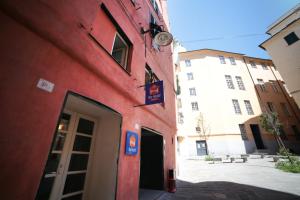 a red building with a door in a street at Abbey Hostel in Genoa