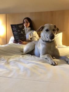 a woman sitting on a bed with a dog at Ibis Ripollet in Ripollet