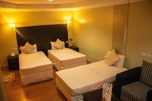 um quarto de hotel com duas camas e um sofá em Panone Hotels - Sakina em Arusha