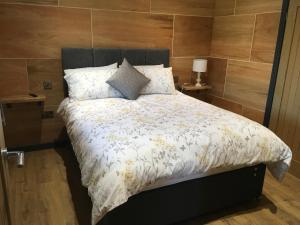 a bed with a white comforter and pillows at Famau Cabins Gwel Y mynudd in Cilcain