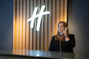 a woman talking on a cell phone in front of a microphone at Holiday Inn Bolton Centre, an IHG Hotel in Bolton