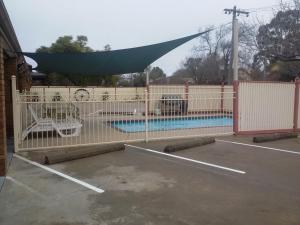 a white fence with a swimming pool behind it at SHEPPARTON MOTOR INN Tudor House Motel in Shepparton