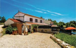 Biały dom z pomarańczowym parasolem przed nim w obiekcie One-Bedroom Holiday Home In Bartici w mieście Barbići