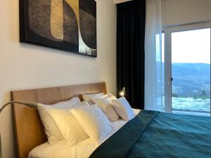 sypialnia z łóżkiem z białymi poduszkami i oknem w obiekcie Apartamenty Kalina z widokiem na góry - Kilińskiego w Świeradowie Zdroju