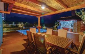 eine Terrasse mit einem Holztisch, Stühlen und einem Pool in der Unterkunft Gorgeous Home In Nerezine With House Sea View in Nerezine