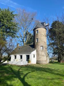 uma casa velha com uma torre num campo de relva em Le moulin de La Retardière em Orvault