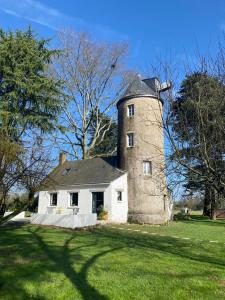 una casa vieja con una torre en un campo de hierba en Le moulin de La Retardière en Orvault