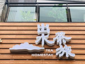 a sign for a tea company on the side of a building at 出水茶旅民宿 in Zhuqi