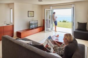 a woman sitting on a couch reading a book in a living room at Il Leccio - Luxury Resort Portofino Monte in Santa Margherita Ligure