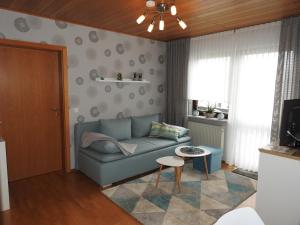 - un salon avec un canapé bleu et une table dans l'établissement Weindl's Ferienwohnung, à Naila