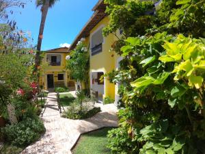 a garden in front of a yellow house at Aguamarinha Pousada in Porto De Galinhas