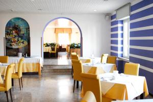 a dining room with white tables and yellow chairs at Hotel Benacus in Lazise