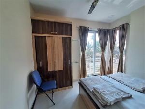 a bedroom with a bed and a chair and a window at Hotel Grand Murud janjira in Murud
