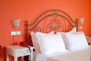 an orange bedroom with a bed with white pillows and a red phone at Hotel Benacus in Lazise