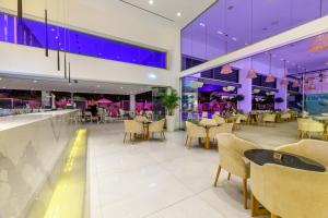 a restaurant with tables and chairs and purple lighting at Seasons Hotel (Adults Only) in Ayia Napa