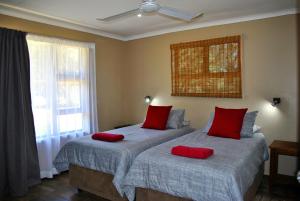sypialnia z 2 łóżkami i czerwonymi poduszkami w obiekcie Forest View Cabins w mieście Tzaneen