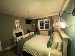 een slaapkamer met een bed met een lamp en een open haard bij The Carriers Arms in Codford Saint Mary