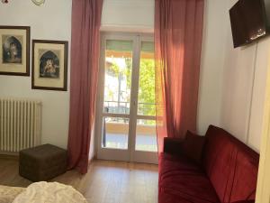 een woonkamer met een rode bank en een glazen schuifdeur bij Affittacamere Il Piccolo Borgo Foligno in Foligno