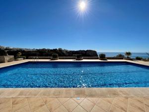 a large swimming pool with the ocean in the background at Apartamento Luz ZM109 in Benitachell