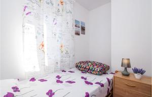 een slaapkamer met een bed met paarse bloemen erop bij Nice Apartment In Vinjerac With Kitchen in Vinjerac