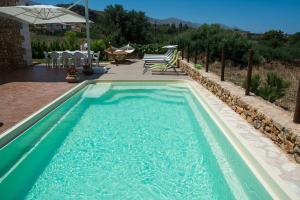 a swimming pool with blue water in a backyard at Villa Calabianca in Castellammare del Golfo