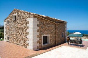 un edificio in pietra con una panchina di fronte di Villa Calabianca a Castellammare del Golfo