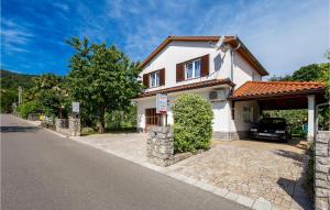 a white house with a car parked in the driveway at Nice Apartment In Rukavac With Wifi in Rukavac