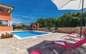 a swimming pool with two chairs and an umbrella at Stunning Apartment In Liznjan With Kitchen in Ližnjan