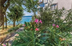 a garden with pink flowers in front of a building at Pet Friendly Apartment In Selce With House Sea View in Selce
