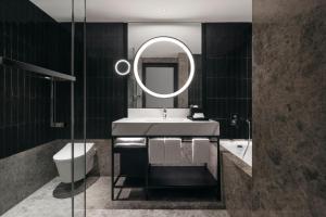 
a bathroom with a toilet, sink, and mirror at Hilton Singapore Orchard - SG Clean in Singapore
