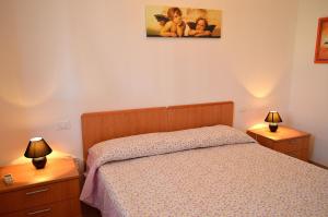 a bedroom with a bed and two night stands with lamps at Appartamento Agrusa in San Vito lo Capo
