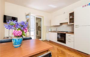 a kitchen with a vase with purple flowers on a table at 2 Bedroom Awesome Apartment In Stara Novalja in Stara Novalja