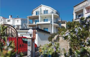 a white building with a red fence in front of it at Two-Bedroom Apartment In Brodarica in Brodarica