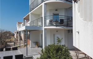 a white building with a balcony with chairs on it at Two-Bedroom Apartment In Brodarica in Brodarica