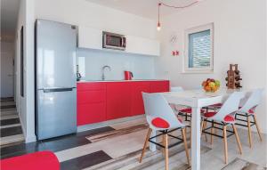 a kitchen with red cabinets and a white table and chairs at Amazing Apartment In Brodarica With 2 Bedrooms And Wifi in Brodarica