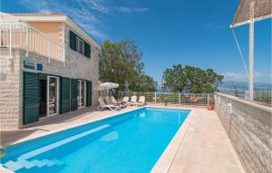 a swimming pool with chairs next to a house at Nice Home In Postira With Wifi in Postira