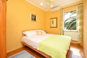 Dormitorio amarillo con cama y ventana en Villa For, en Hvar
