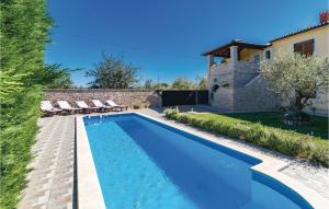 uma piscina com cadeiras e uma casa em Cozy Home In Frkeci With Outdoor Swimming Pool em Barban