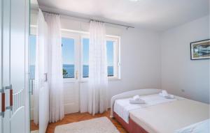 a white bedroom with a bed and a window at Beach Front Home In Omis in Omiš