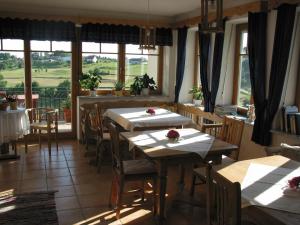 ein Esszimmer mit Tischen, Stühlen und Fenstern in der Unterkunft Landhaus Eder in Stegersbach