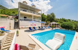 a pool with chairs and umbrellas in front of a house at Lovely Home In Trsteno With Private Swimming Pool, Can Be Inside Or Outside in Trsteno