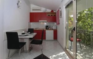 a kitchen with red cabinets and a table and chairs at Nice Apartment In Arbanija With 1 Bedrooms And Wifi in Trogir