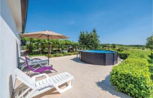 a patio with two chairs and an umbrella and a pool at Cozy Apartment In Pican With Kitchen in Pićan