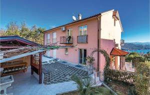 a large pink house with a balcony on a hill at Nice Apartment In Volosko With Kitchen in Volosko
